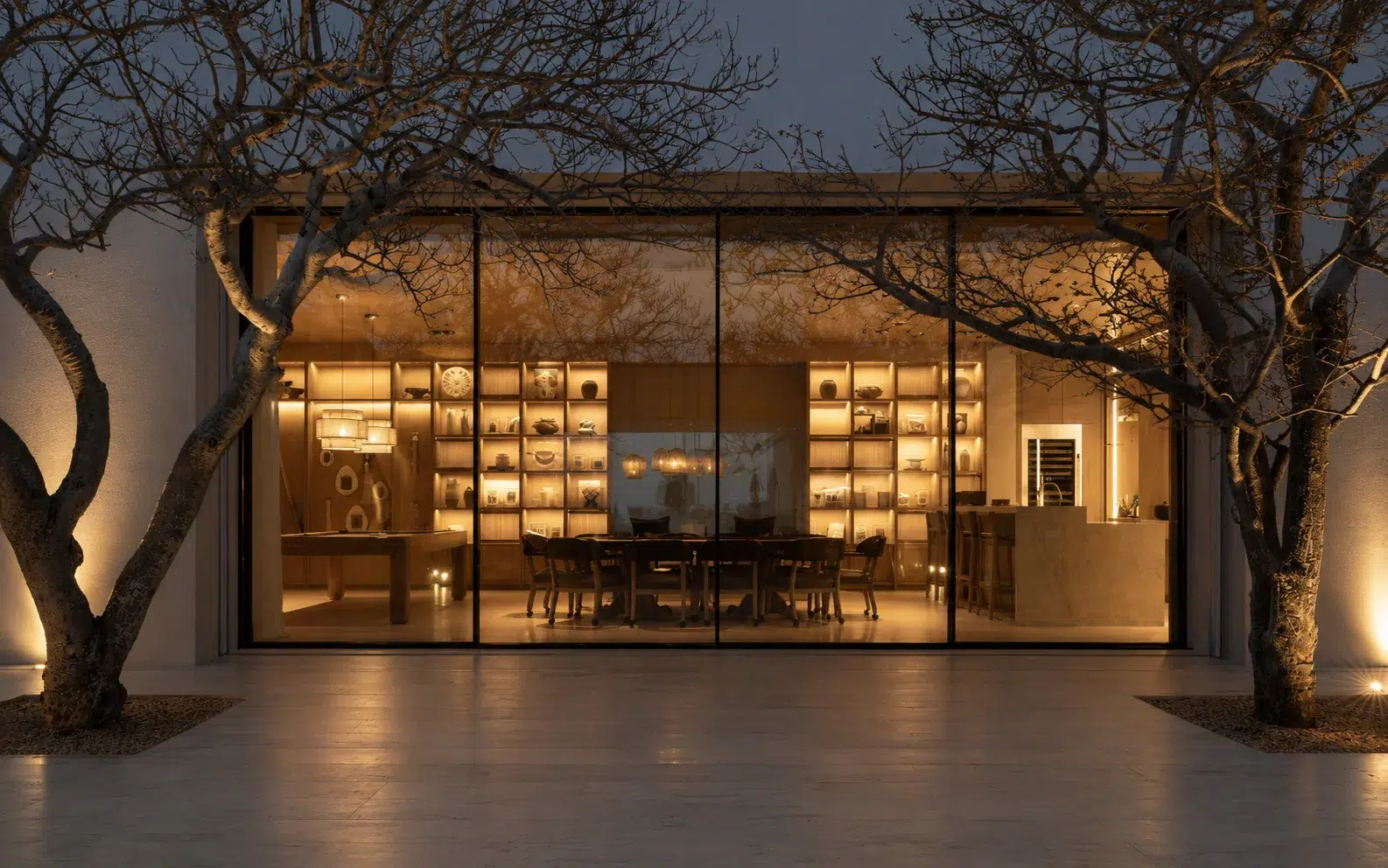 Wide panoramic sliding door opening viewed from a landscaped courtyard at night